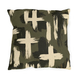 Cream and black brushstroke crosses on an olive green outdoor pillow