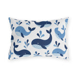 Coastal outdoor lumbar pillow with tossed navy and sky blue whales with water spouts on white
