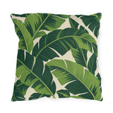 Tropical outdoor pillow with large overlapping fresh and deep green banana leaves on cream