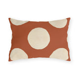 Modern polka dot outdoor lumbar pillow with large hand painted cream dots on terracotta orange