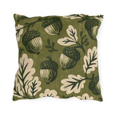 Acorns and oak leaves in forest green and cream on a mossy olive outdoor pillow