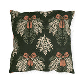Cream cedar fronds and terracotta bows on a near-black forest green outdoor pillow