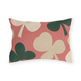 Modern outdoor lumbar pillow with oversized cream and forest green clover leaves on coral pink