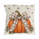 Orange pumpkin with a taupe gingham bow and eucalyptus on a cream polka dot outdoor pillow