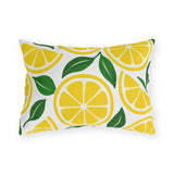 Yellow outdoor lumbar pillow with lemon slices and green leaves on white