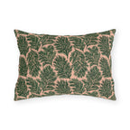 Dark green pine sprigs on blush peach outdoor lumbar pillow