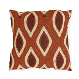 Cream and oxblood ikat teardrops on a burnt terracotta outdoor pillow