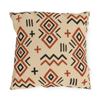 Boho mudcloth outdoor pillow with terracotta and black diamonds, zigzags and crosses on sand