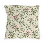 Christmas mistletoe outdoor pillow with sage green sprigs, white berries and thin red bows on warm cream