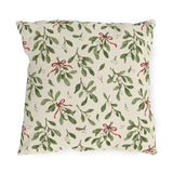 Christmas mistletoe outdoor pillow with sage green sprigs, white berries and thin red bows on warm cream