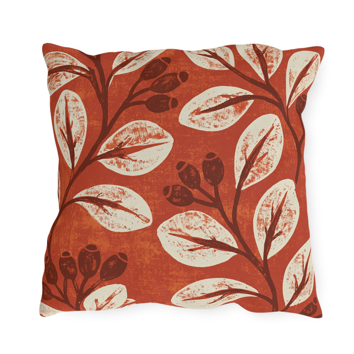 Cream leaves and dark rosehips block printed on a burnt terracotta outdoor pillow