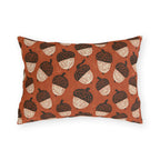 Block-printed cream and dark brown acorns on rust orange outdoor lumbar pillow