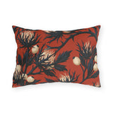 Navy sea holly thistles with cream heads on a brick red outdoor lumbar pillow