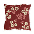 Cream blossoms on rose branches over a deep brick red outdoor pillow