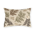Cedar sprigs in brown, olive and tan scattered on a cream outdoor lumbar pillow