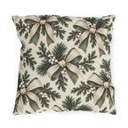 Ivory and sage ribbon bows on cedar sprigs with white berries on a cream outdoor pillow