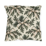 Ivory and sage ribbon bows on cedar sprigs with white berries on a cream outdoor pillow
