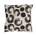 Black brush rings and solid dots on an oatmeal outdoor pillow