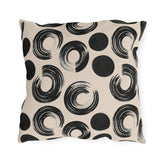 Black brush rings and solid dots on an oatmeal outdoor pillow