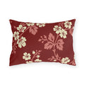 Cream blossoms on rose branches over a deep brick red outdoor lumbar pillow