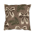Cream and chocolate bows with spruce sprigs on a warm brown outdoor pillow