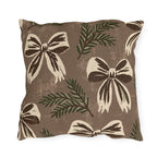 Cream and chocolate bows with spruce sprigs on a warm brown outdoor pillow