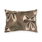 Cream and chocolate bows with spruce sprigs on a warm brown outdoor lumbar pillow