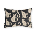 Cream folk art cats on a near-black outdoor lumbar pillow, worn block print
