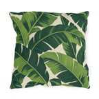 Tropical outdoor pillow with large overlapping fresh and deep green banana leaves on cream