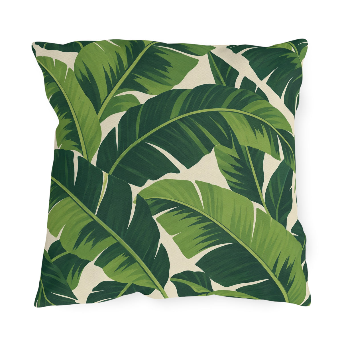 Tropical outdoor pillow with large overlapping fresh and deep green banana leaves on cream