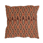 Nested ikat diamonds in charcoal and cream on a burnt rust outdoor pillow