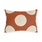 Modern polka dot outdoor lumbar pillow with large hand painted cream dots on terracotta orange