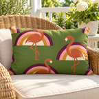 Olive retro rainbow flamingo outdoor lumbar pillow styled on a rattan lounge chair on a sunny deck