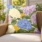 Periwinkle hydrangea outdoor pillow on a rattan chair on a sunny porch