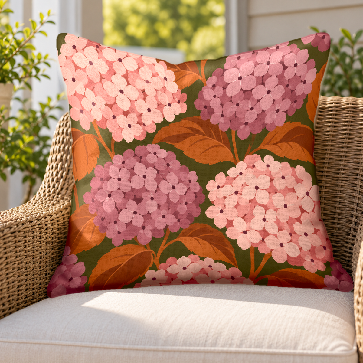 Blush hydrangea outdoor pillow on a rattan chair on a sunny porch