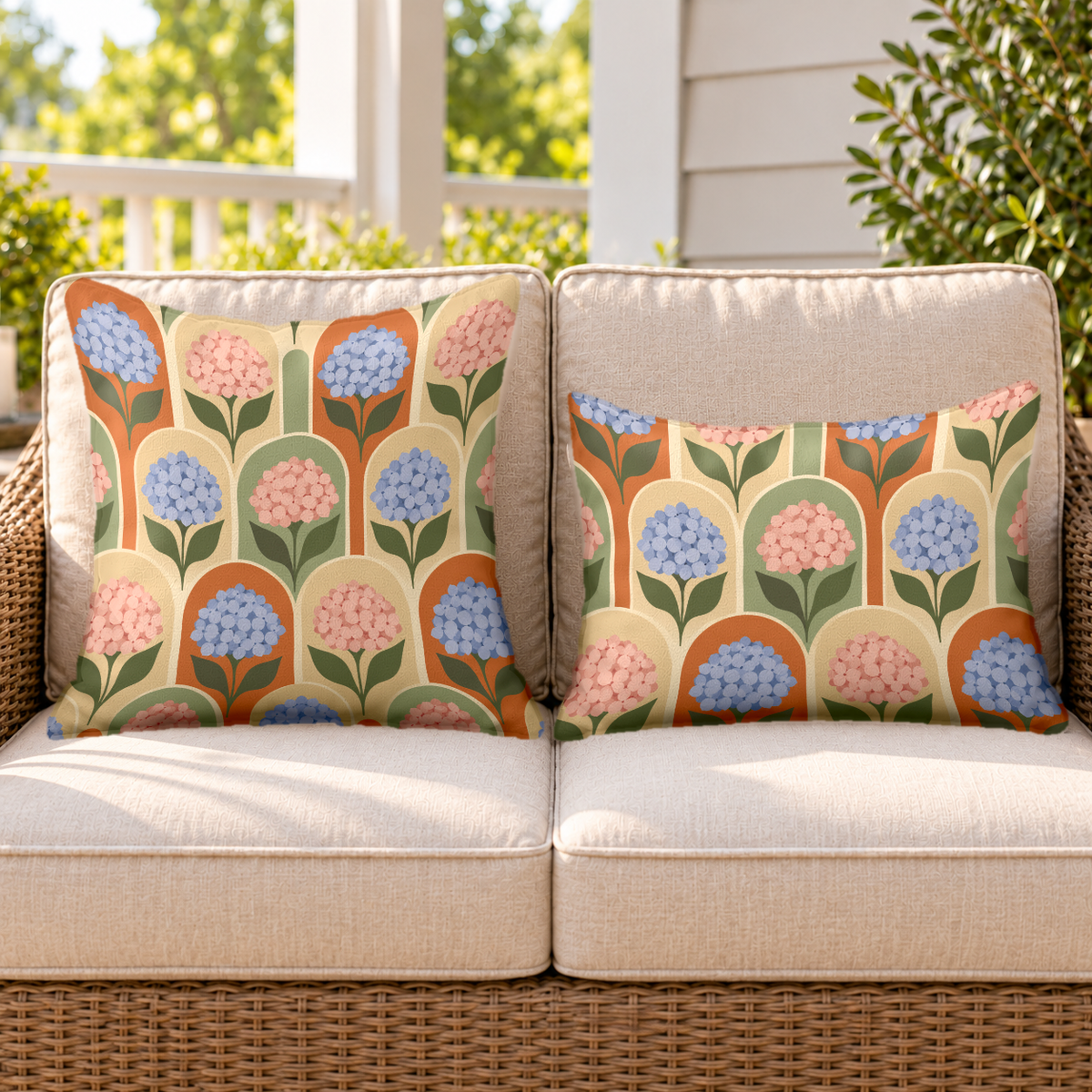 Terracotta hydrangea arch outdoor pillow and outdoor lumbar pillow styled together as a set on a wicker loveseat