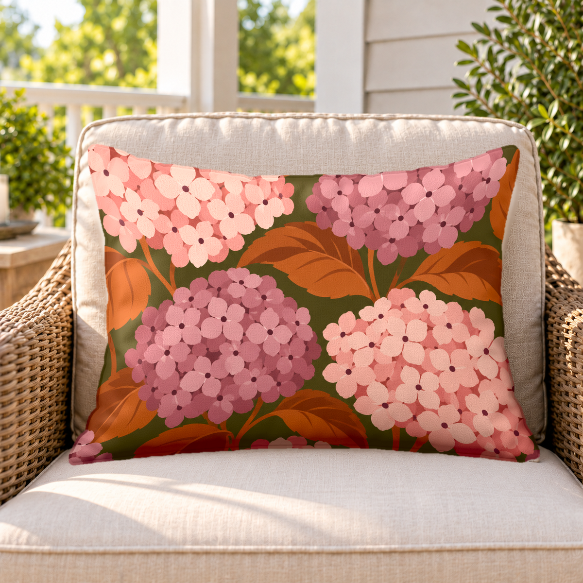 Blush hydrangea outdoor lumbar pillow on a rattan chair on a sunny porch
