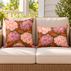 Blush hydrangea outdoor pillow and outdoor lumbar pillow styled together as a set on a wicker loveseat