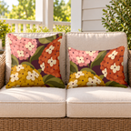 Plum mid-century hydrangea outdoor pillow and outdoor lumbar pillow styled together as a set on a wicker loveseat
