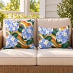 Blue groovy hydrangea outdoor pillow and outdoor lumbar pillow styled together as a set on a wicker loveseat