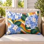 Blue groovy hydrangea outdoor lumbar pillow on a rattan chair on a sunny porch