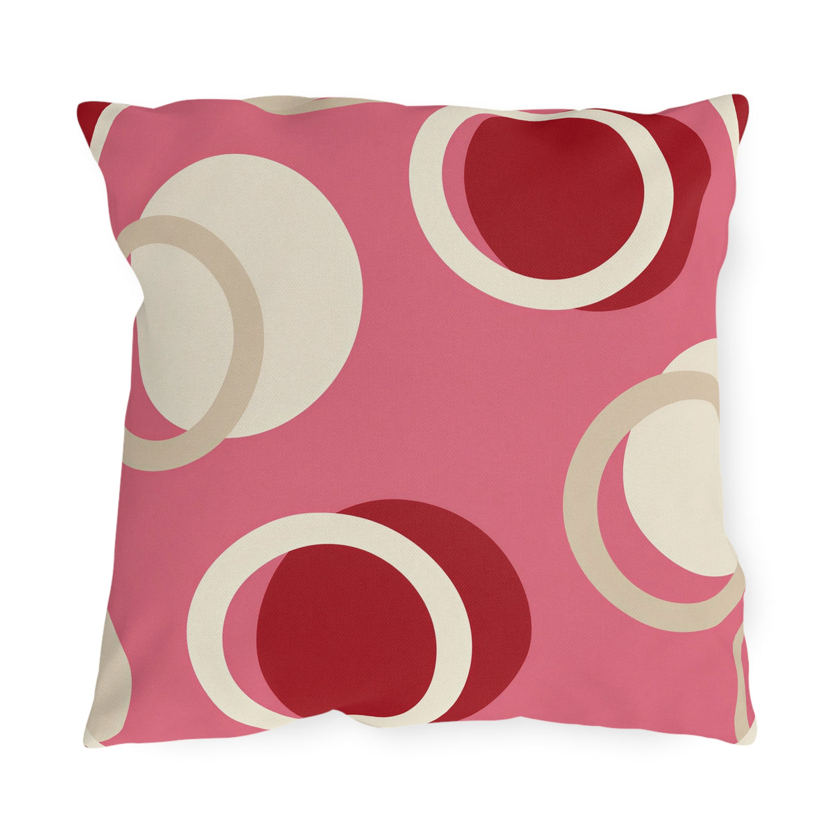 Modern outdoor pillow with overlapping cream rings and cherry red circles on bright pink