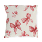 Pink outdoor pillow with hand-drawn rose pink ribbon bows and small flower sprigs on cream
