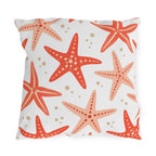 Coastal outdoor pillow with tossed coral and peach starfish and sandy dots on white