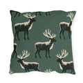 Black and cream block print stags on a deep forest green outdoor pillow