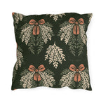 Cream cedar fronds and terracotta bows on a near-black forest green outdoor pillow