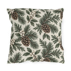 Pine branches, cedar sprigs, pinecones and white berries on a cream outdoor pillow