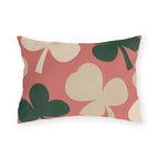 Modern outdoor lumbar pillow with oversized cream and forest green clover leaves on coral pink