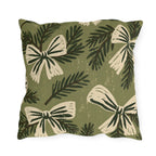 Cream bows and dark spruce sprigs on a soft sage green outdoor pillow