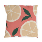 Modern outdoor pillow with oversized cream citrus slices and dark green leaves on coral pink